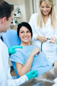 patient in dental chair with dr and assistant